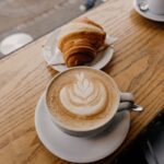 cup of cappuccino near croissant bread