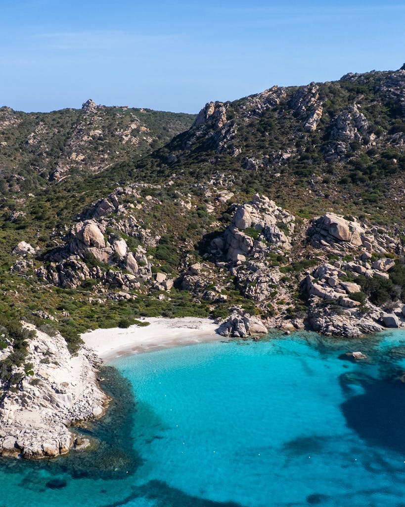 A stunning view of a secluded beach with turquoise waters surrounded by rocky terrain.