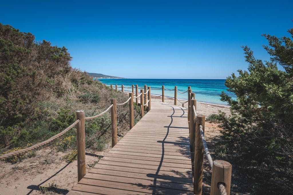 Picturesque wooden boardwalk leading to a serene beach under clear blue skies.
