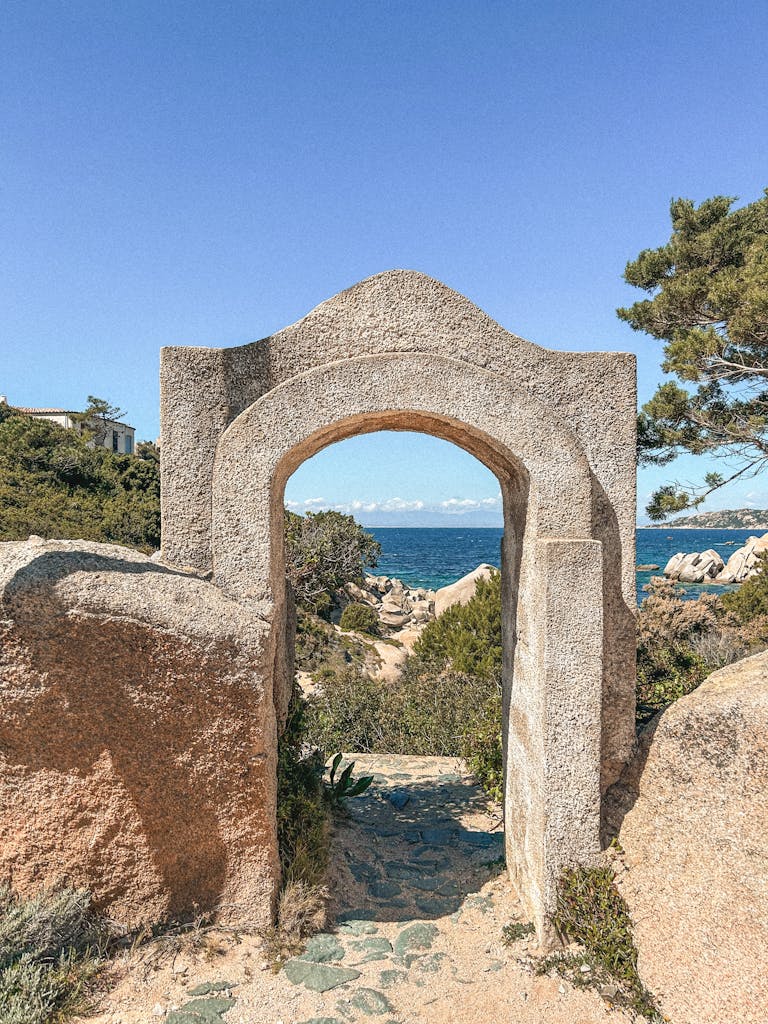 Scenic view through a historic stone archway, capturing the beauty of the Sardinian coastline.