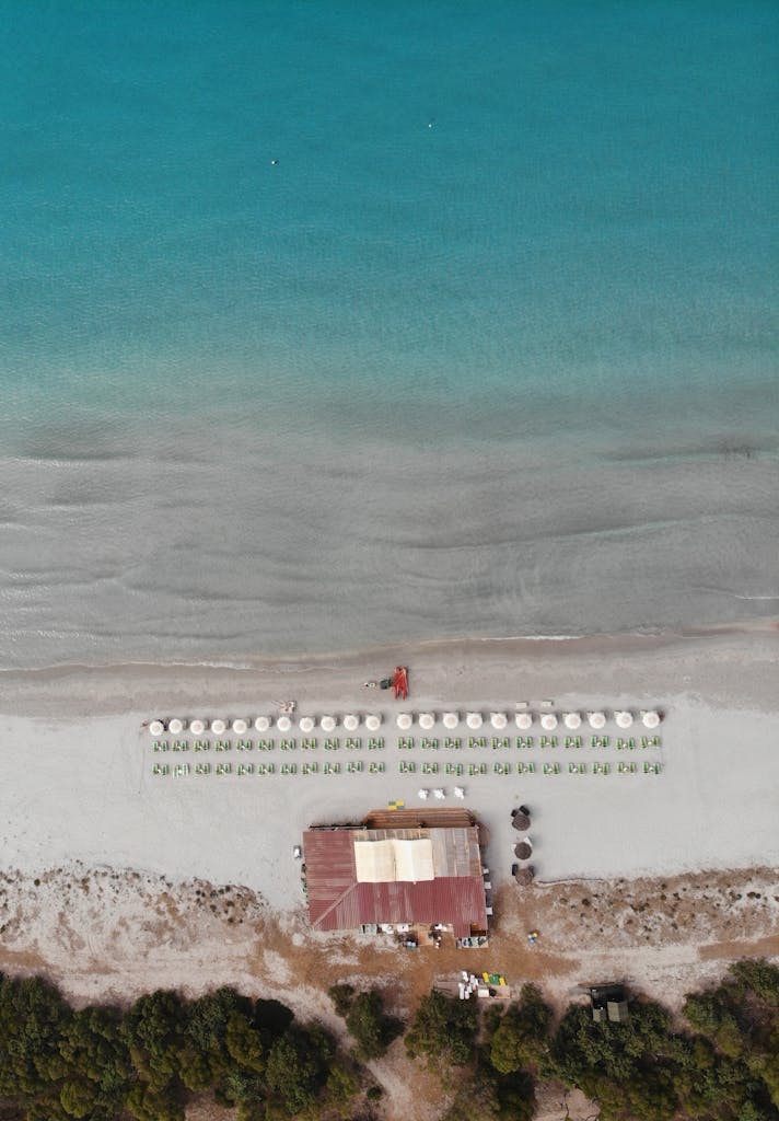 Stunning aerial shot of Porto Pino beach with deckchairs and umbrellas on a sunny day.
