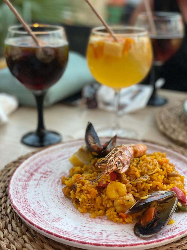 Vibrant seafood paella served with sangria, capturing Spanish flavors in an inviting outdoor setting.