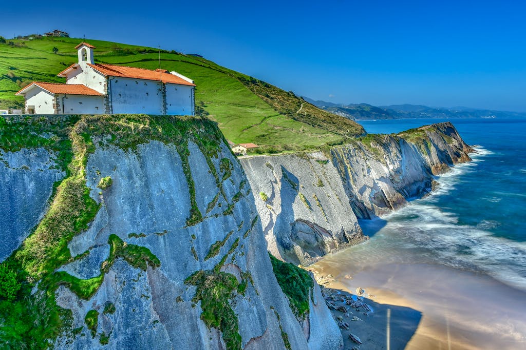 View of a charming chapel perched on vibrant cliffs overlooking the sea in Zumaya, Spain.